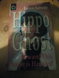 front cover of Lance Salway's Hippo Ghost, a book for younger readers - cover design overcast by my shadow as I took the photo